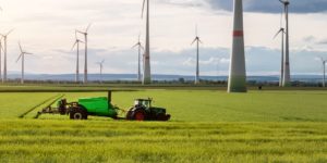 trator de rodas operando no campo junto a torres de energia eolica