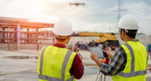 engenheiros operando drone em canteiro de obras