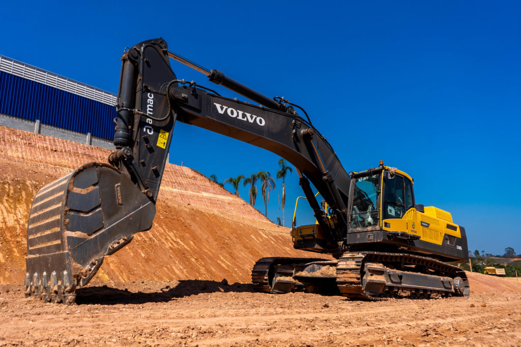 escavadeira volvo na garagem extrena da Armac, a céu aberto, em um terreno de terra