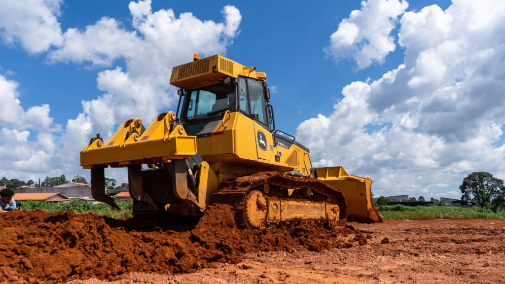 Trator de esteira John Deere da Armac em operação em solo argiloso, utilizado para terraplanagem e movimentação de terra