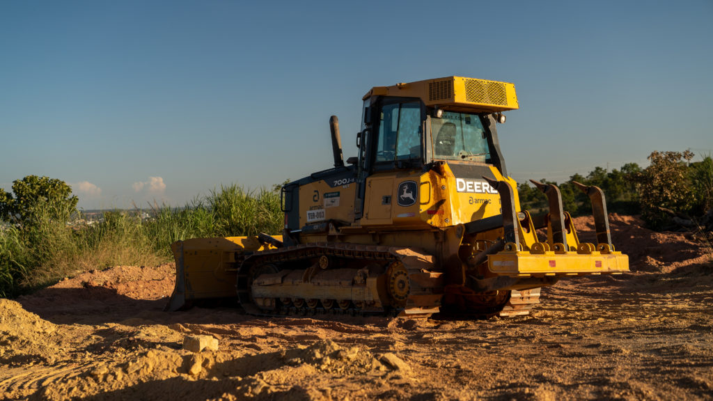 Trator de esteira John Deere 700J da Armac em operação em canteiro de obras, utilizado em movimentação de terra e nivelamento de terrenos